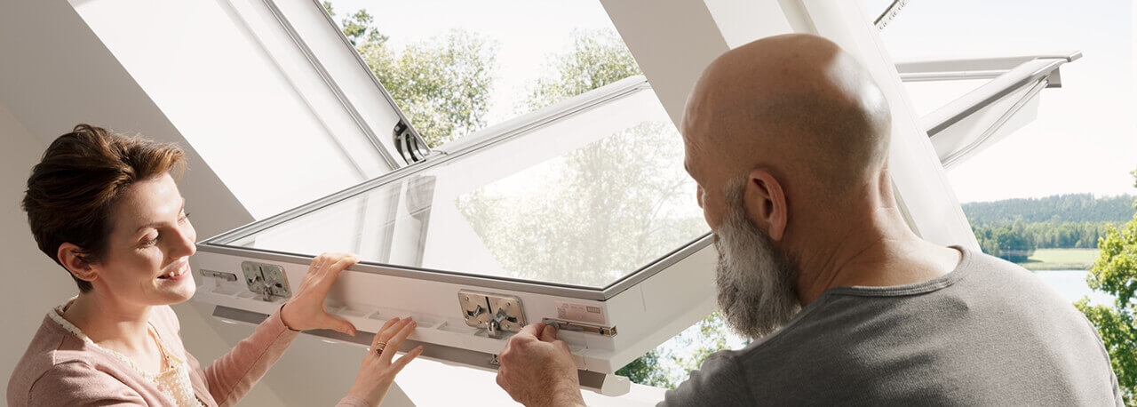 Un uomo e una donna osservano la funzione di comando di una finestra per tetti VELUX.