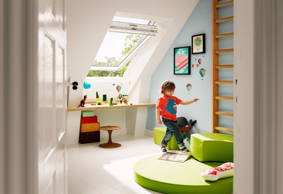 Ein kleiner Junge spielt in einem farbenfrohen Raum, hinter ihm befindet sich ein grosses VELUX Dachfenster.