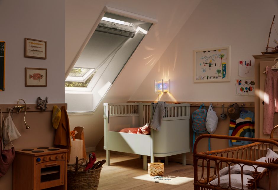 Ein Babyzimmer mit Kinderbett und Spielzeug ist mit einem VELUX Dachfenster und Verdunkelungsrollo vor Tageslicht geschützt.